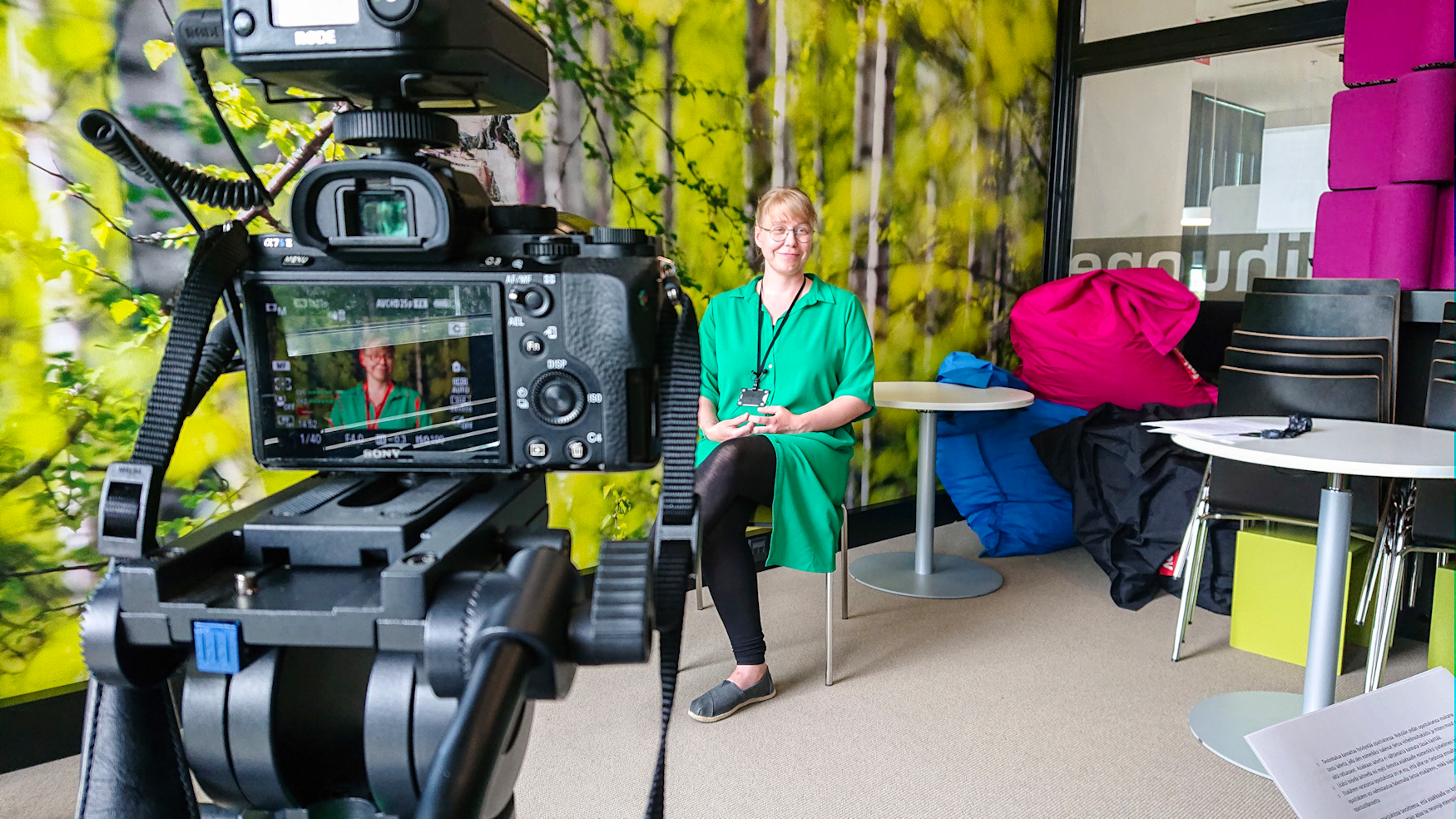 Making of -kuva videokuvauksista Lielahden kirjastossa. Kuvassa on kamera ja mediasihteeri Laura Aatola.