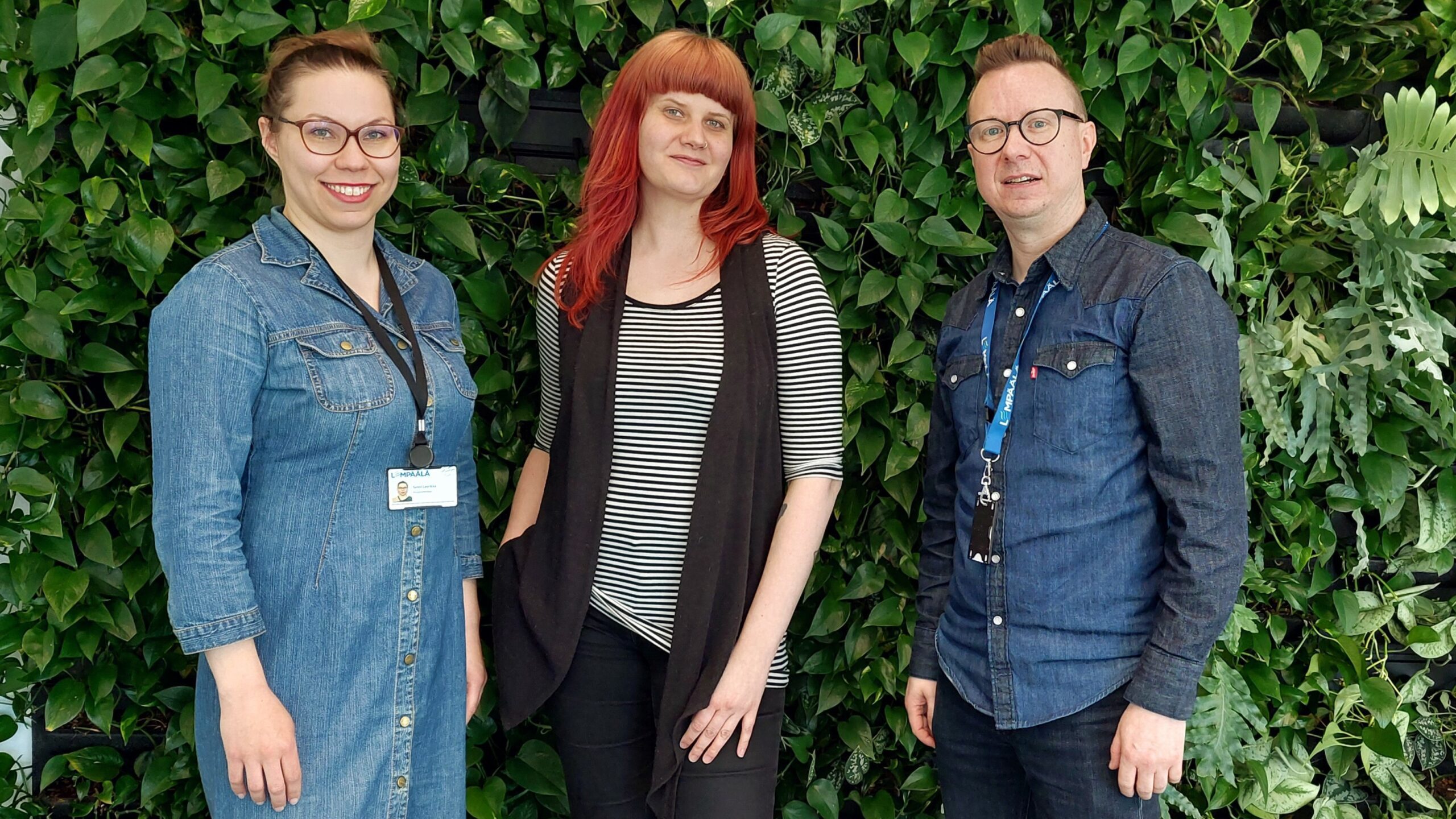 Kolme ihmistä rinnakkain viherseinän edessä.