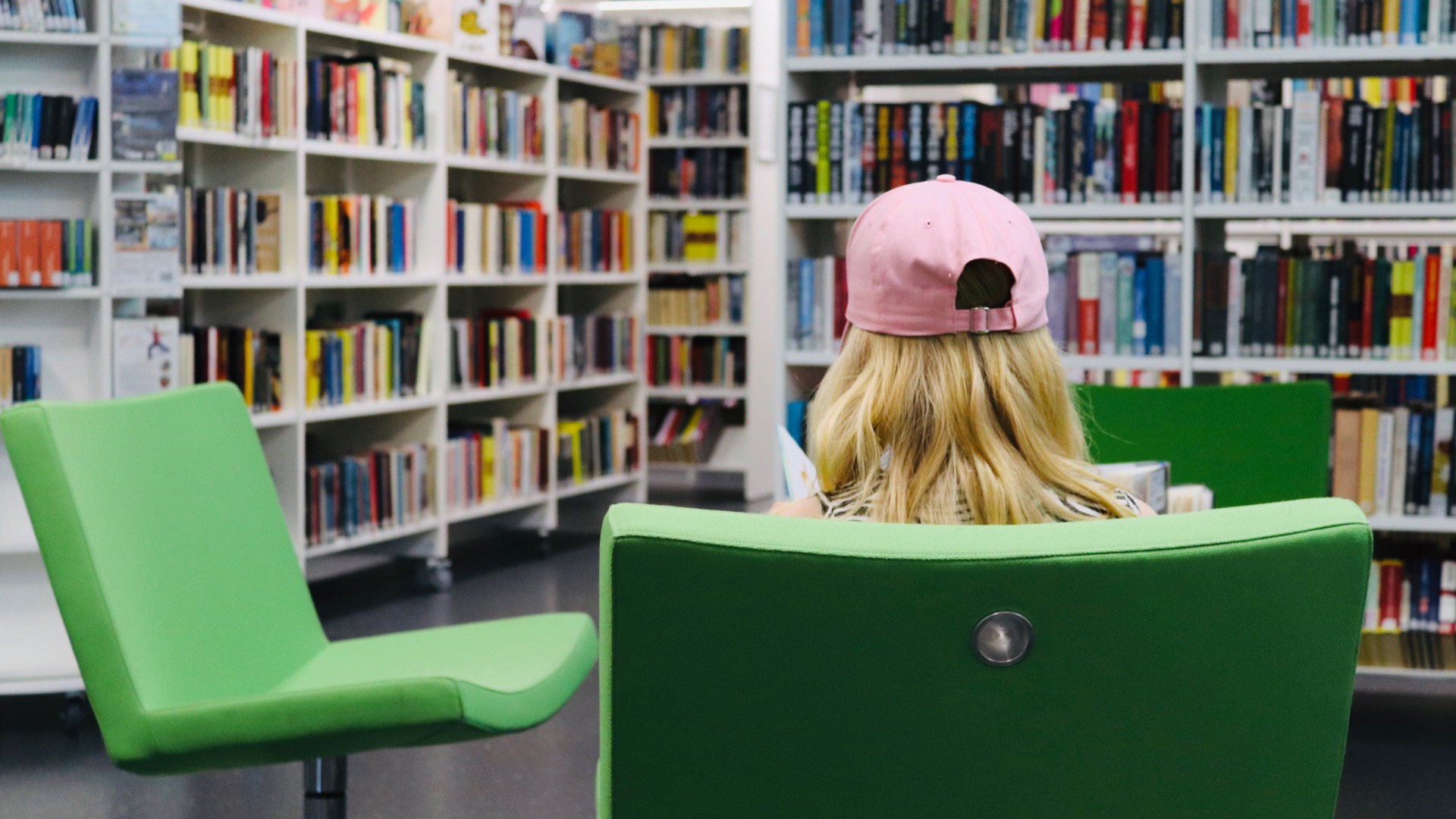 Kuvassa asiakas istuu nojatuolissa Parkanon kirjastossa. Takana näkyy kirjaston kokoelmahyllyjä, joissa kirjoja.