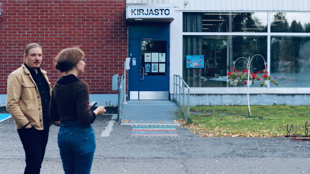 Projektisuunnittelijat Kalle Lehtinen ja Juliaana Grahn Juupajoen kirjaston parkkipaikalla. Takana näkyy kirjaston sisäänkäynti ja ikkunoita.