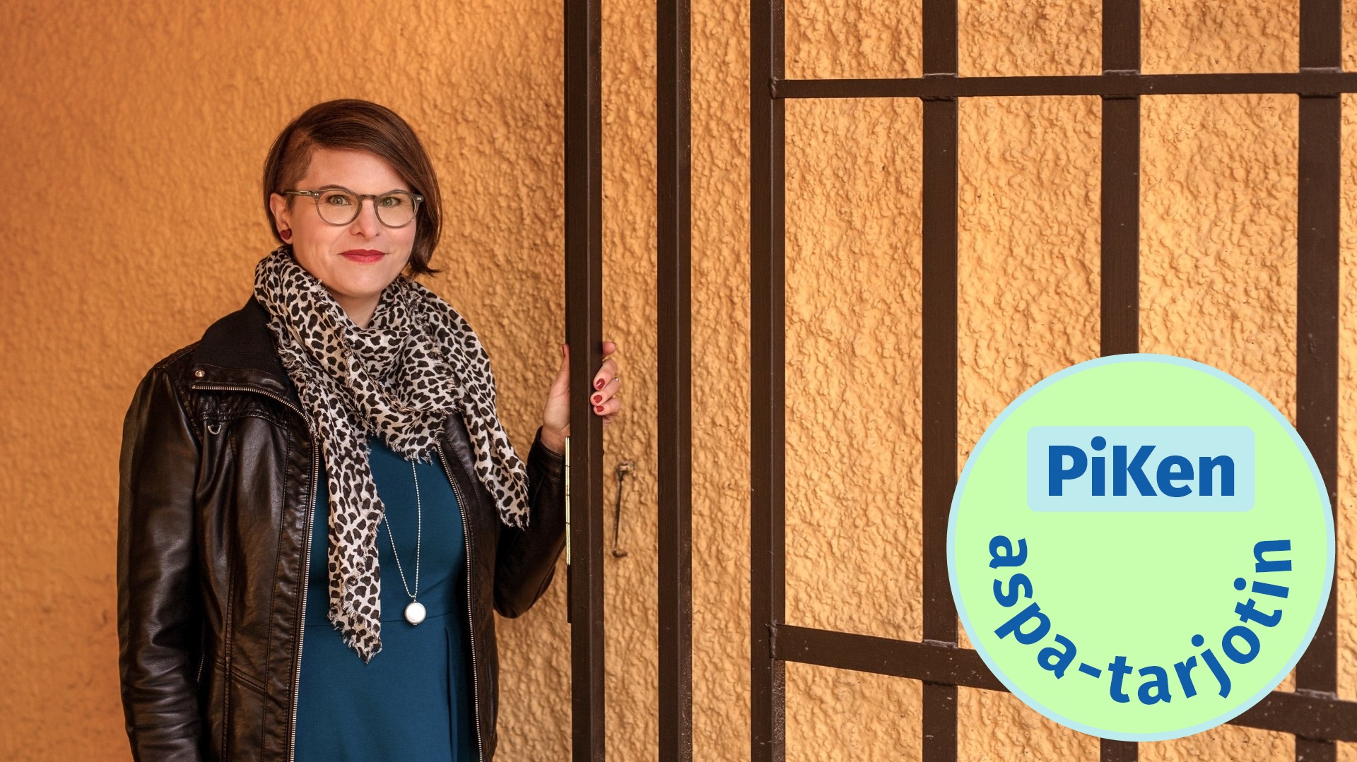 Henkilö seisoo rapatun seinän edessä ja pitää kiinni rautaisesta portista. Vihreä PiKen aspa-tarjotin -logo oikeassa alakulmassa.