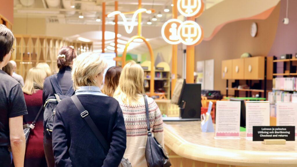 Ihmisiä kirjastotilassa selkä kameraan päin.