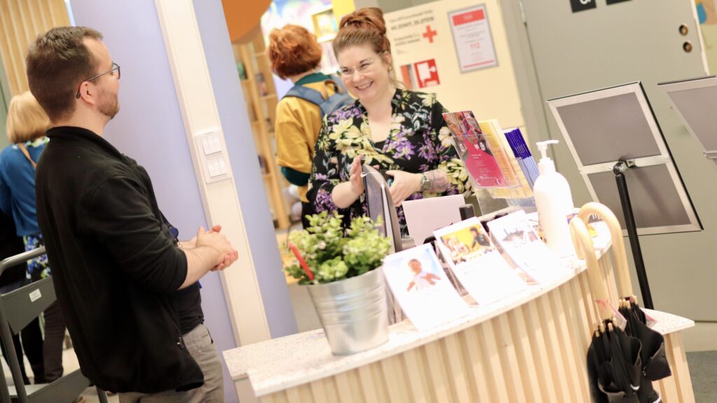 Kaksi ihmistä kirjaston asiakaspalvelupisteellä keskustelemassa.