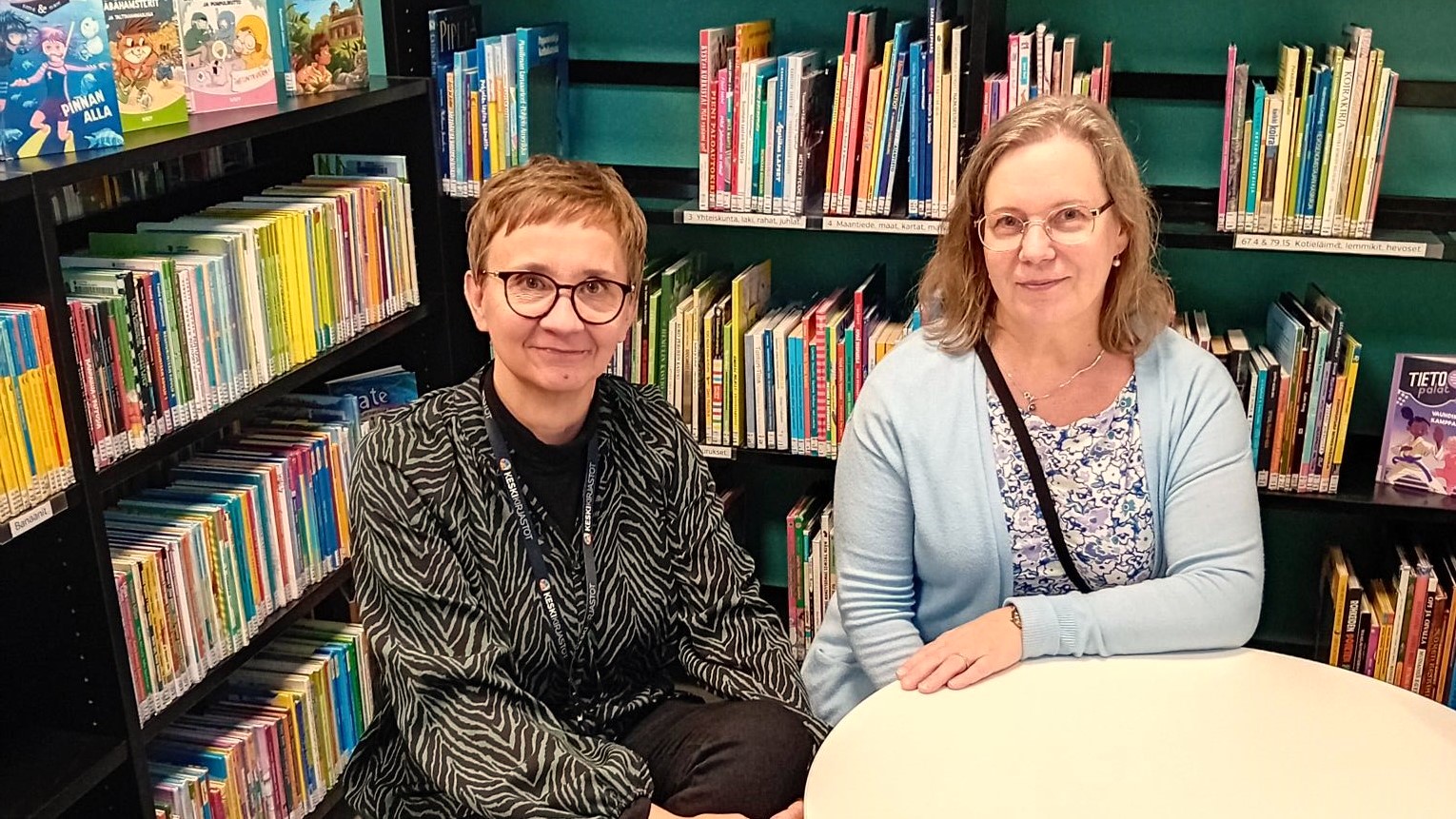 Kaksi ihmistä pöydän ääressä kirjastossa