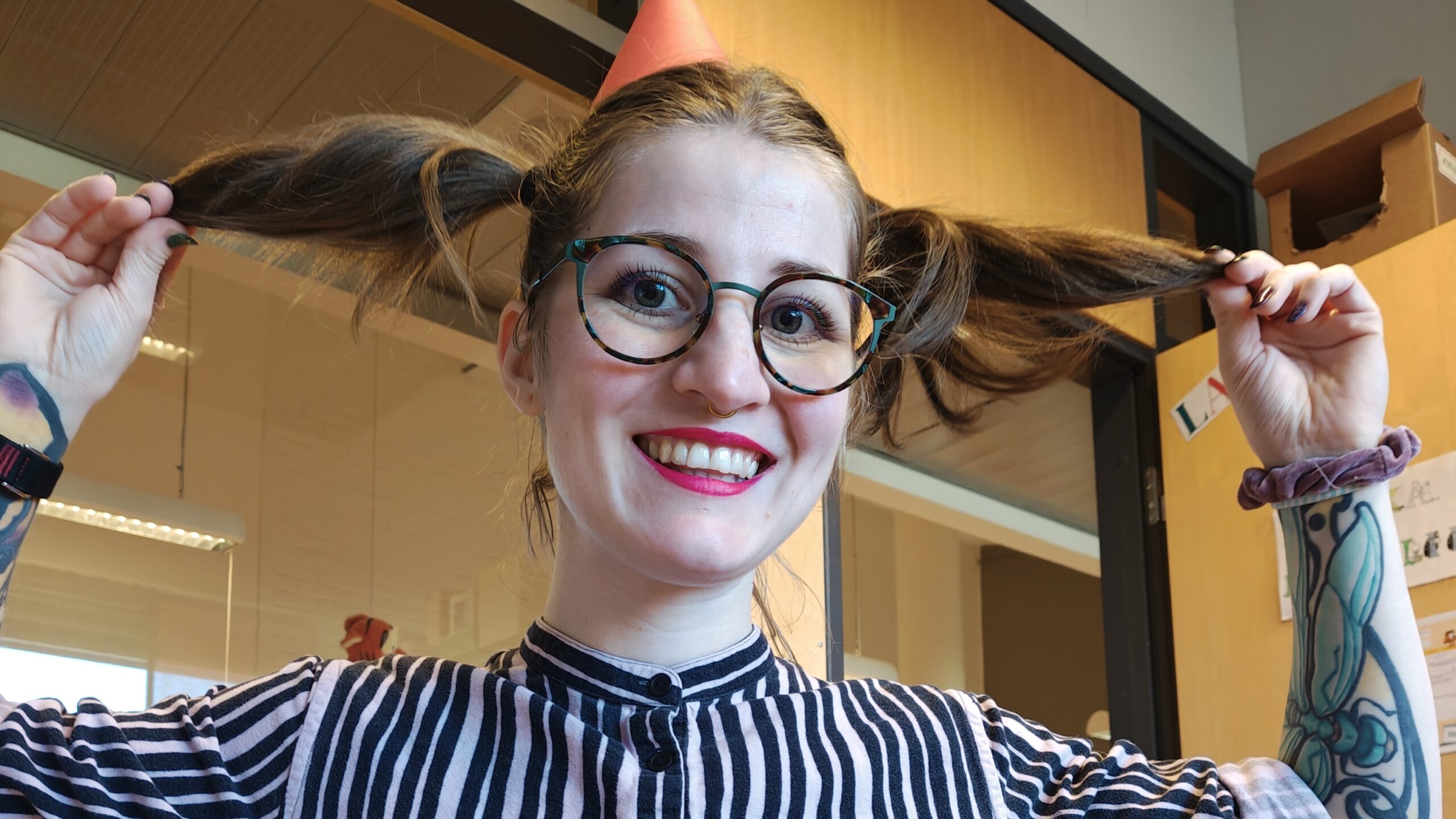 Satutäti Pikkiriikki lähikuvassa, hiukset käsien varassa nostettuna saparoiksi pään ympärille.