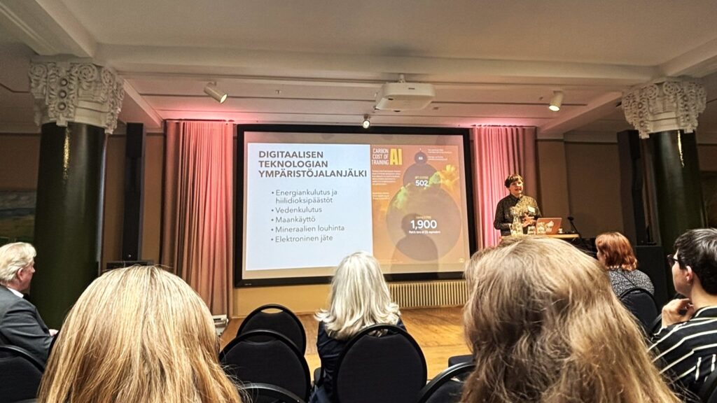 Yleisöä takaa päin kuvattuna kuuntelemassa luennoitsijaa