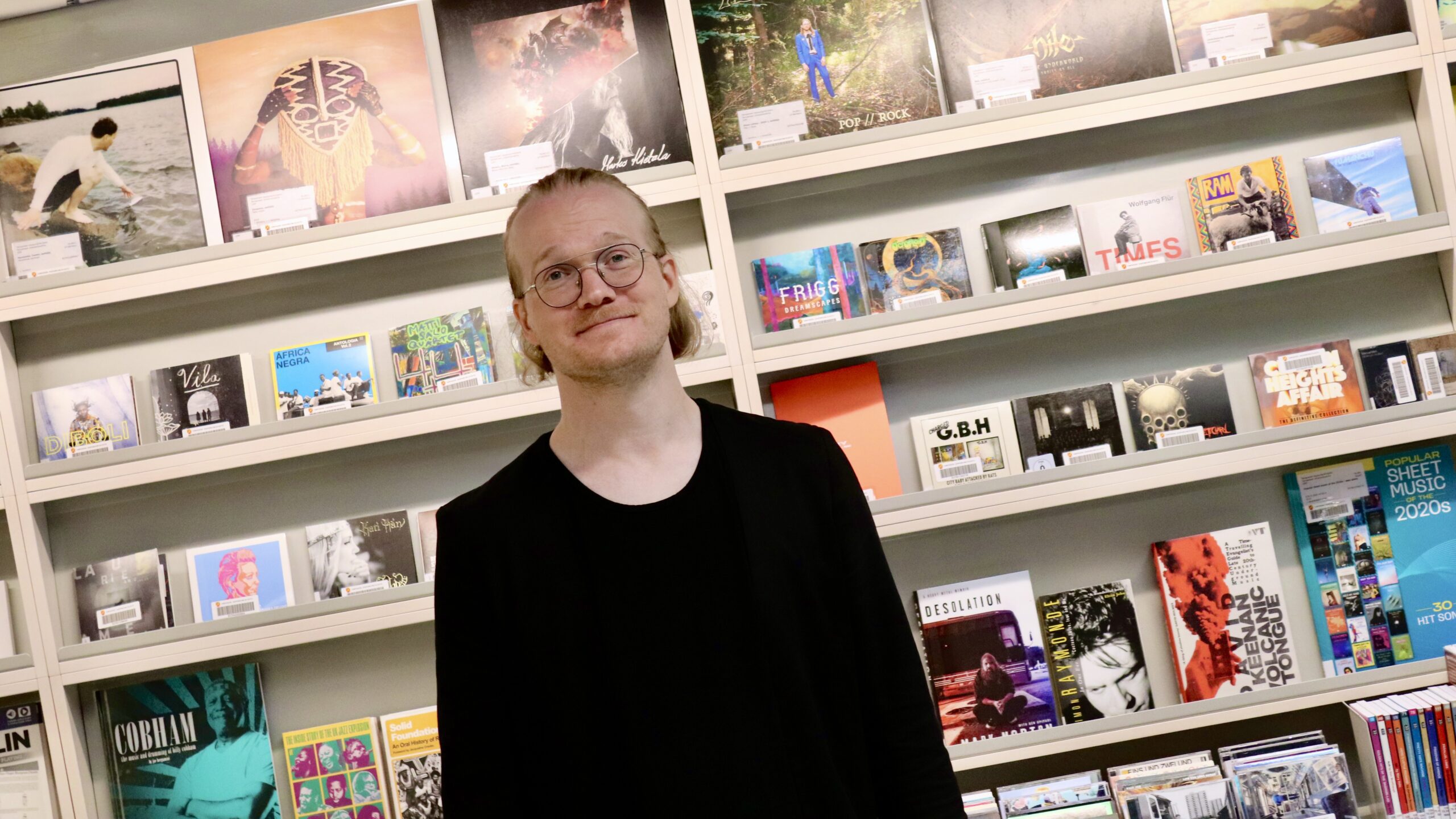 Koordinaattori Pasi levynkansien edustalla pääkirjasto Metsossa.