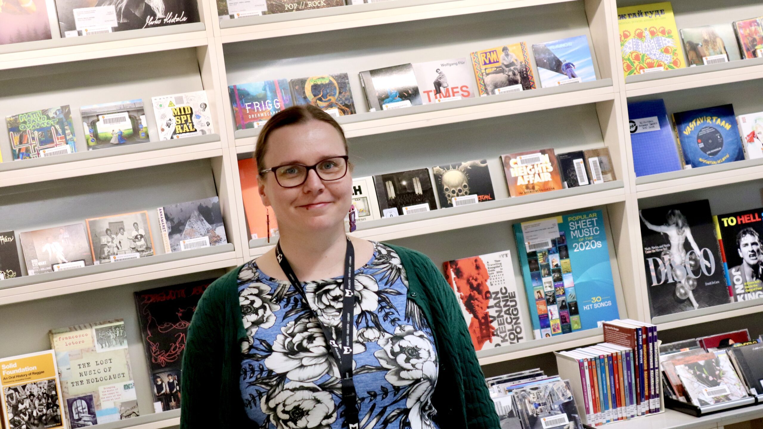 Koordinaattori Kaisa levynkansien edustalla pääkirjasto Metsossa.