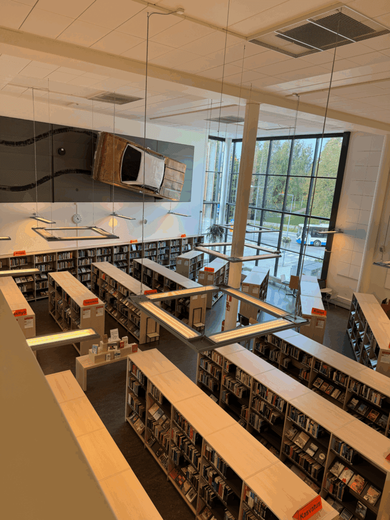 Anssi Kasitonnin tietä pitkin kaartavaa autoa kuvastava teos Kangasalan pääkirjaston seinällä.