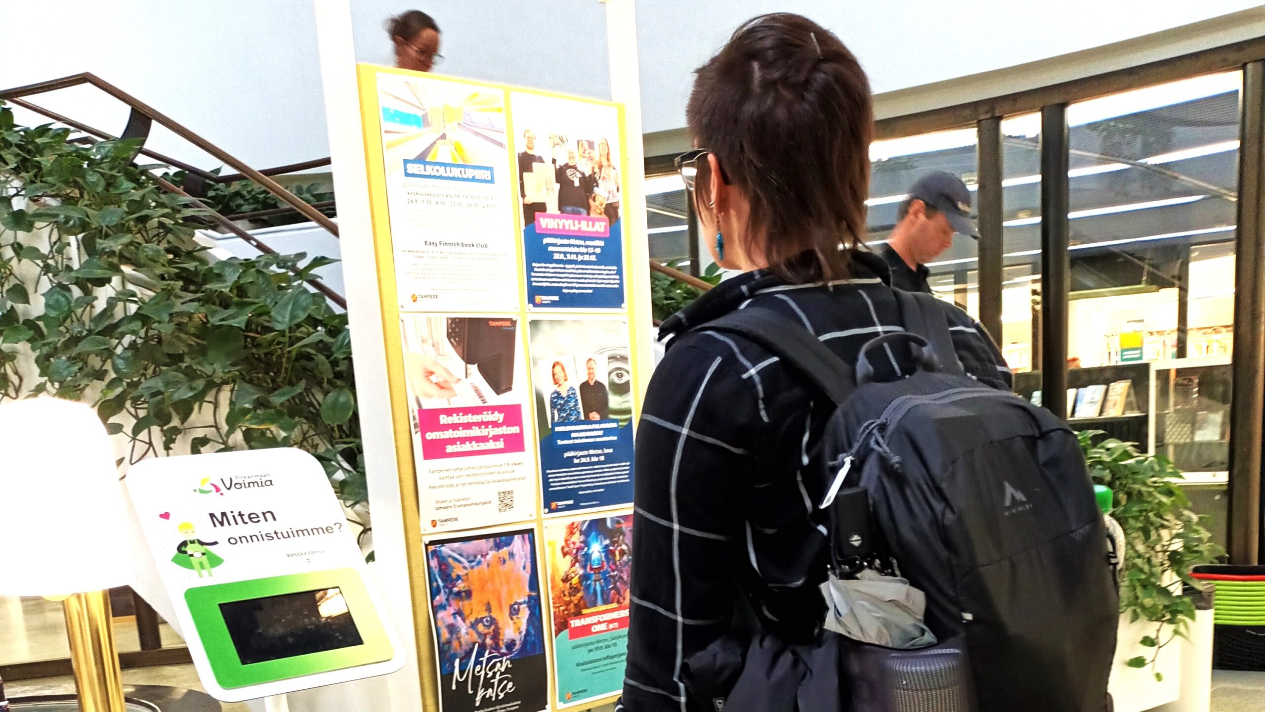 Ihminen katsoo ilmoitustaulua Tampereen pääkirjasto Metson aulassa.