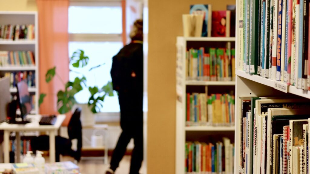 Yleisnäkymä Luhangan pääkirjaston kirjastosaliin. Taustalla värikkäitä seiniä ja verhoja sekä valkoisia kirjahyllyjä täynnä erivärisiä kirjoja.