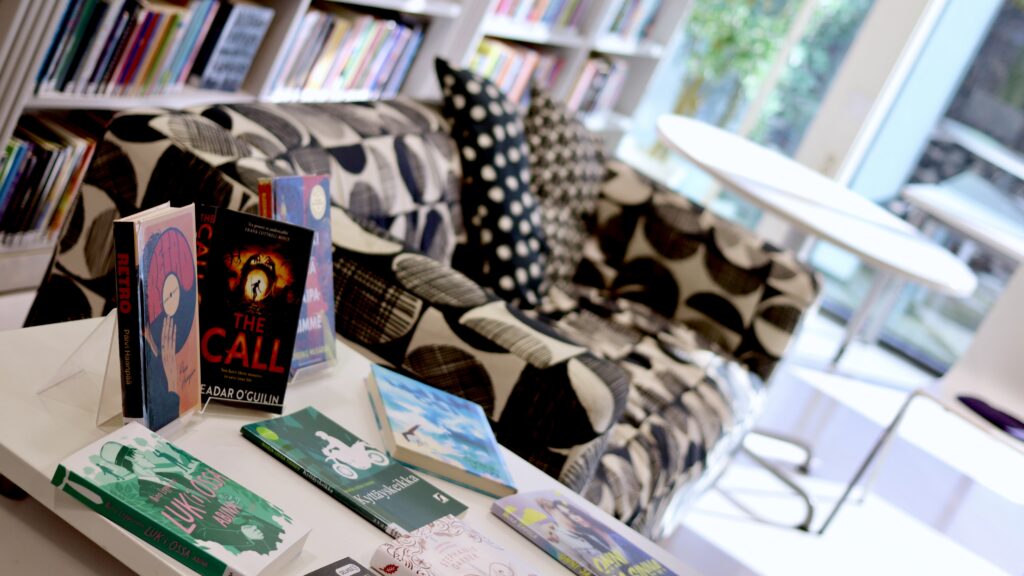 Kirjoja esittelypöydällä kirjastossa, taustalla sohva.