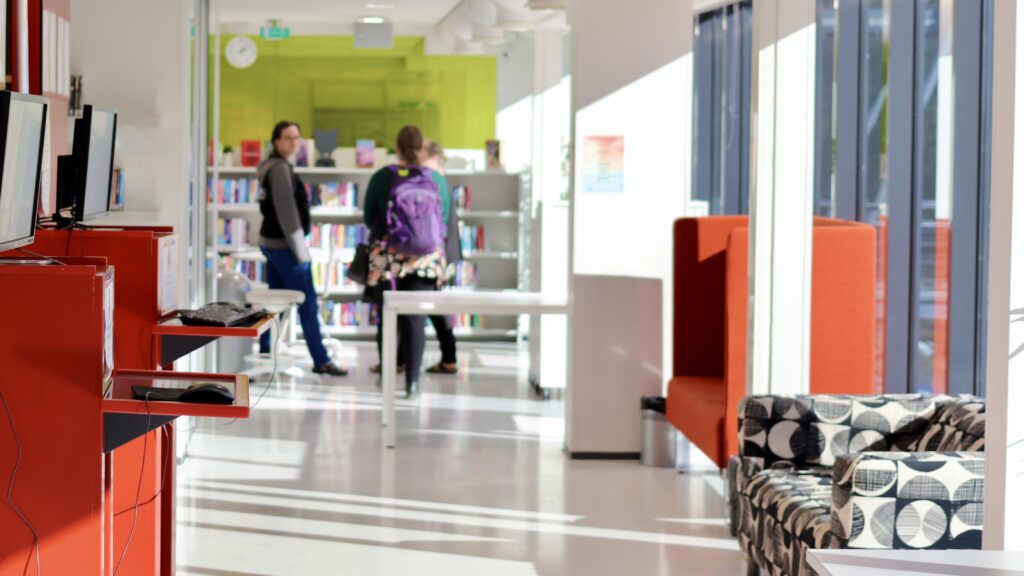 Kuva kirjastosalissa. Taka-alalla kolme ihmistä.