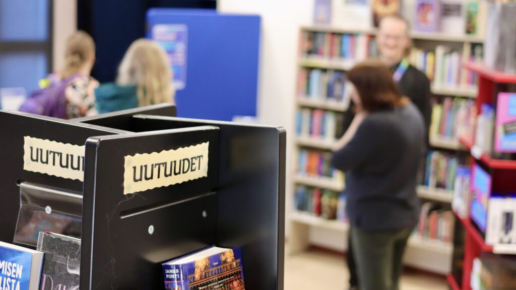 Uutuushylly kirjastossa, taustalla ihmisiä