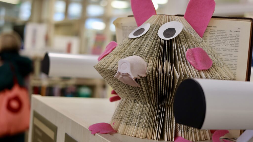 Poistokirjataidetta kirjahyllyn päällä