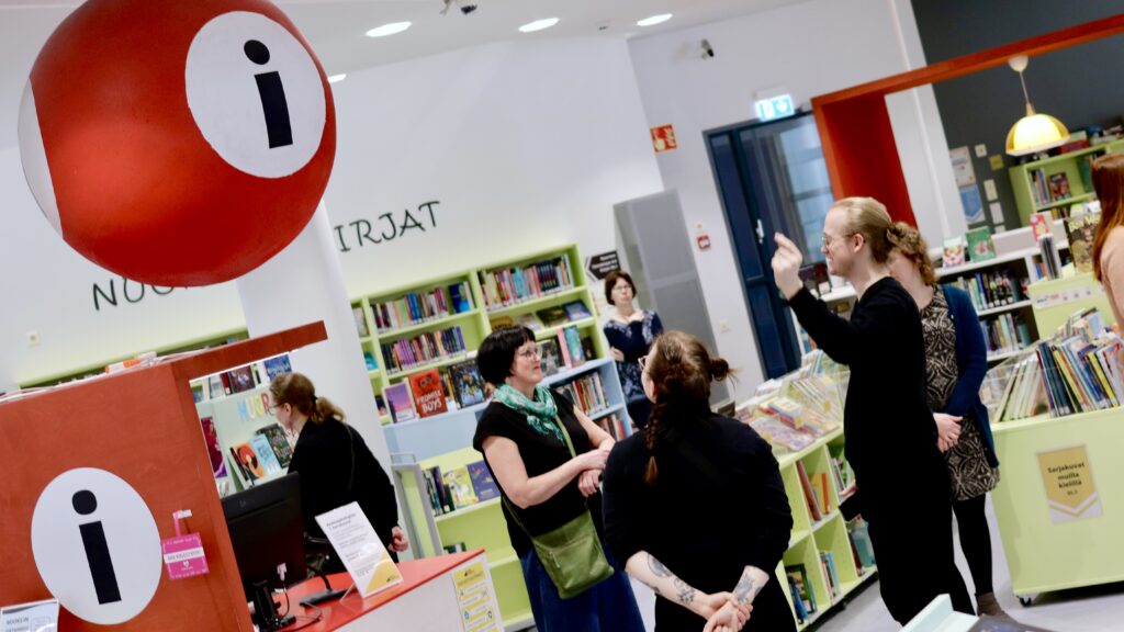 Ihmisiä infopisteen lähellä Joensuun kirjastossa.